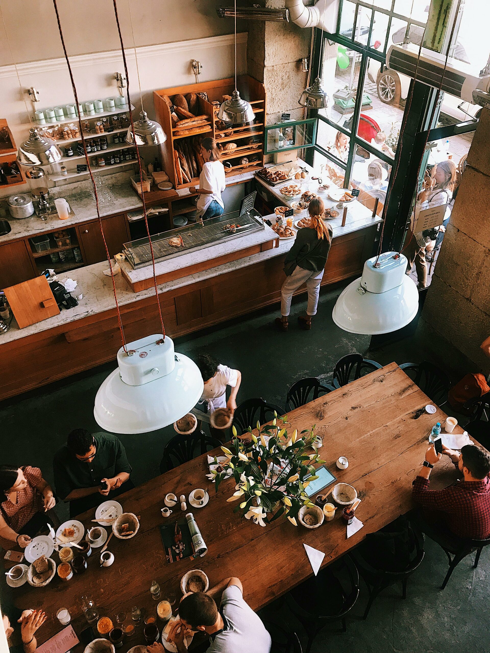 A vibrant aerial view of a busy cafe in Kraków, showcasing patrons enjoying baked goods and coffee.