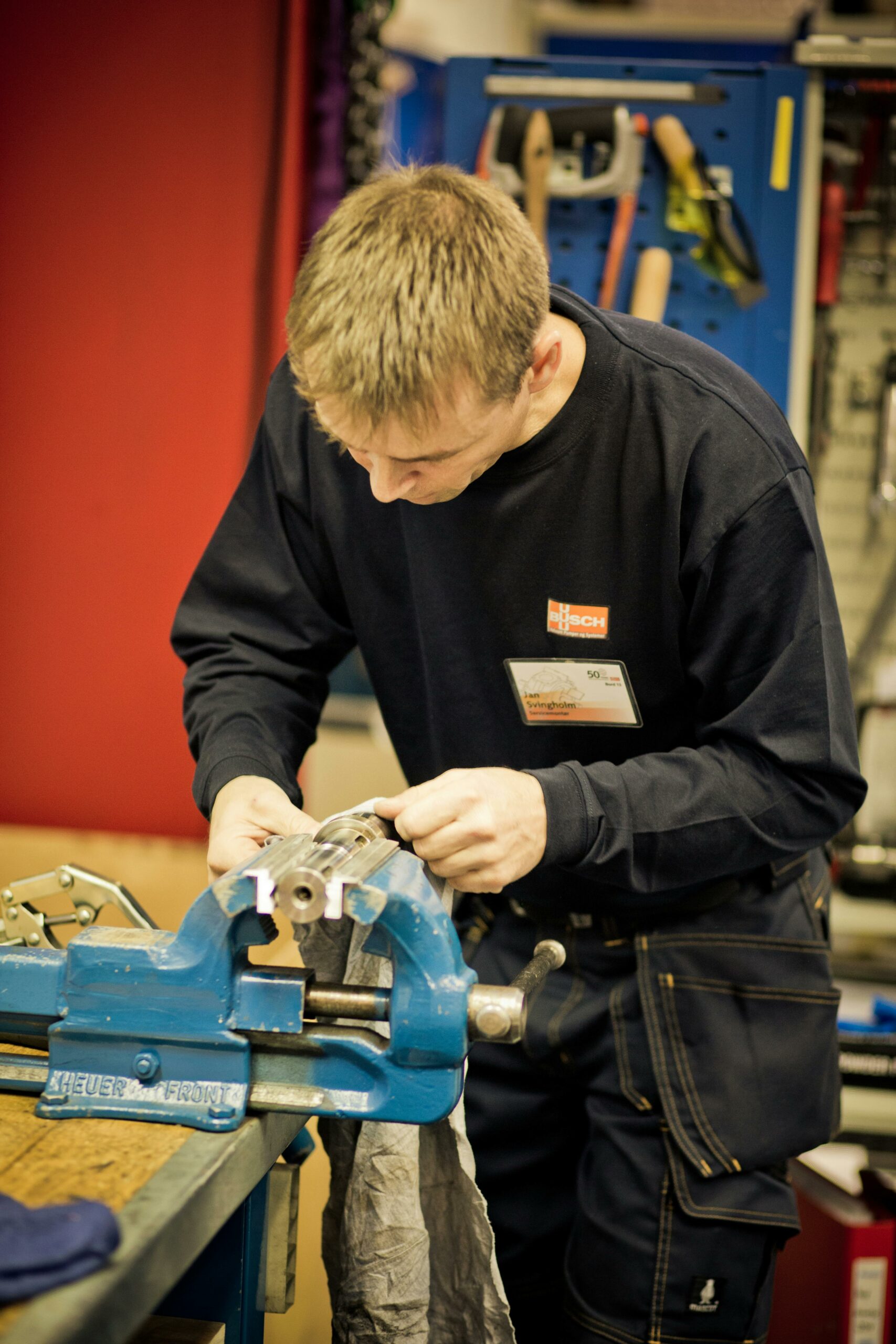 A focused man crafting metal in a workshop with precision tools and equipment.